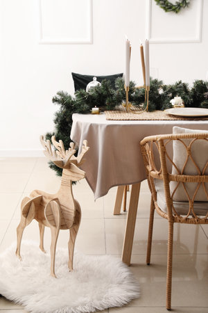 Dining table with beautiful setting for Christmas celebration and wooden reindeer in roomの写真素材