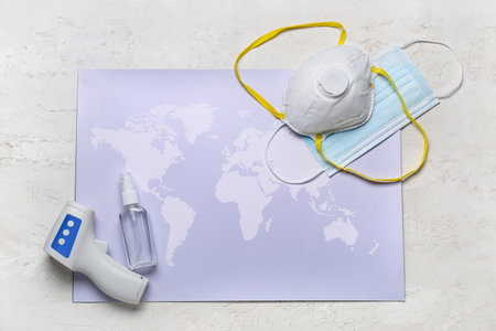 Digital thermometer, bottle with antiseptic, medical masks and map on gray backgroundの写真素材
