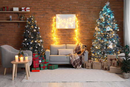 Interior of festive living room with Christmas trees, gray sofa and armchairの写真素材