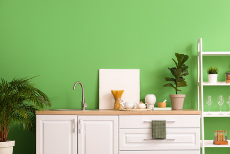 Interior of stylish kitchen with white counters, shelving unit and green wallの写真素材