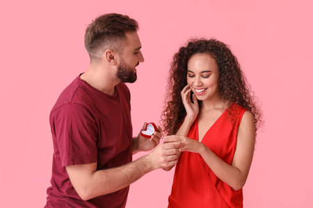 Young man proposing to his girlfriend on color backgroundの写真素材