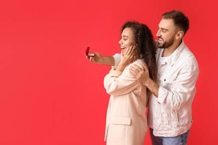 Young man proposing to his girlfriend on color backgroundの写真素材