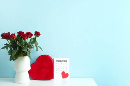 Bouquet of flowers, calendar with marked date of Valentine's Day and gift on table against color backgroundの写真素材