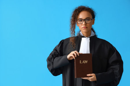 Young female judge with law book on color backgroundの写真素材