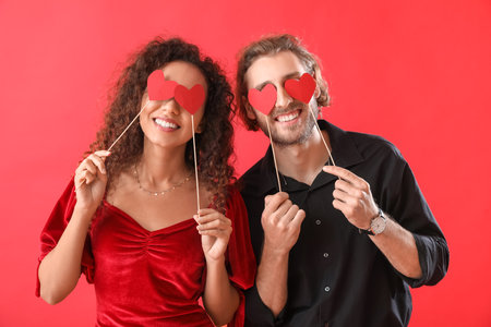 Happy young couple with party decor on color background. Valentine's Day celebrationの写真素材