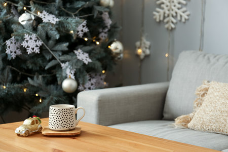 Cup and toy car on wooden table in living room decorated for Christmasの写真素材