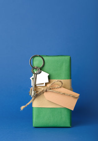 Key from new house with Christmas gift on blue background
