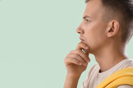 Thoughtful young man on green background, closeupの写真素材