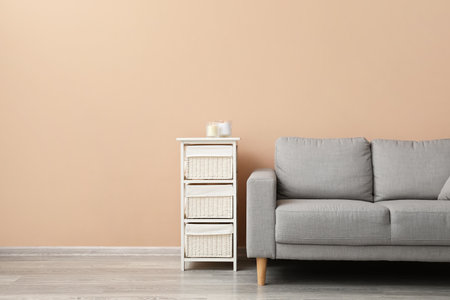Modern chest of drawers with sofa near beige wallの写真素材