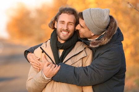 Happy gay couple hugging in autumn parkの写真素材