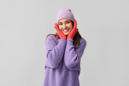 Young woman in red gloves and hat on light backgroundの写真素材