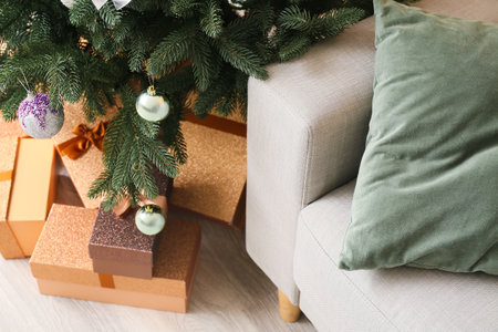 Beautiful Christmas tree with gifts and sofa in room, closeupの写真素材