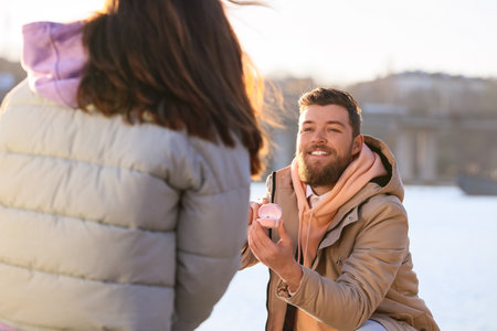 Young man proposing to his girlfriend near the riverの写真素材
