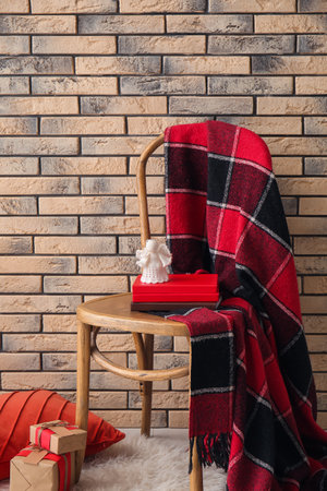 Chair with books, angel toy and gifts near brick wall in room. christmas storyの写真素材