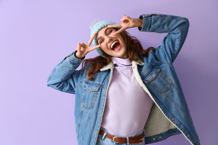 Happy stylish woman in winter clothes on color backgroundの写真素材