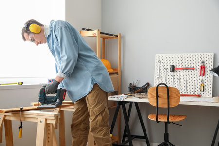 Male carpenter sawing wood in workshopの写真素材