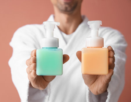 Young man with different liquid soap on color background, closeupの写真素材