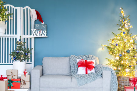 Gray sofa with Christmas trees and folding screen near blue wallの写真素材