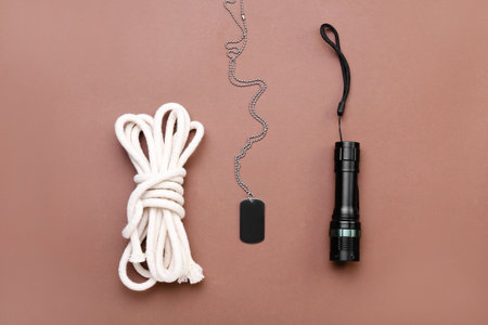 Military tag, flashlight and rope on color background