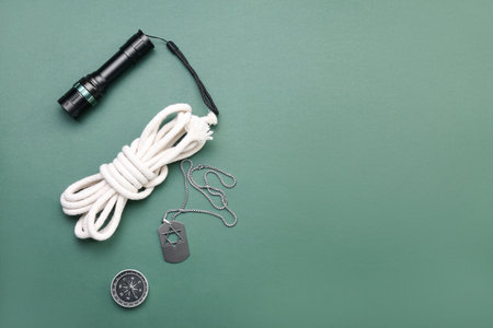 Military tag, flashlight, rope and compass on green background
