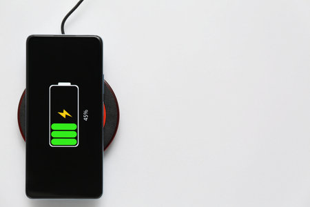 Modern mobile phone charging with wireless pad on gray background