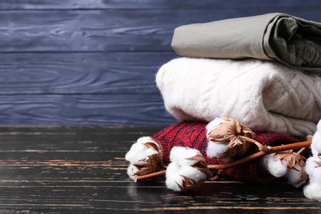 Stack of children's sweaters and cotton flowers on dark wooden backgroundの写真素材