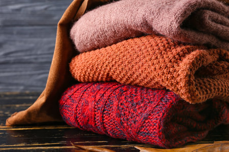 Stack of children's sweaters on dark wooden table, closeupの写真素材