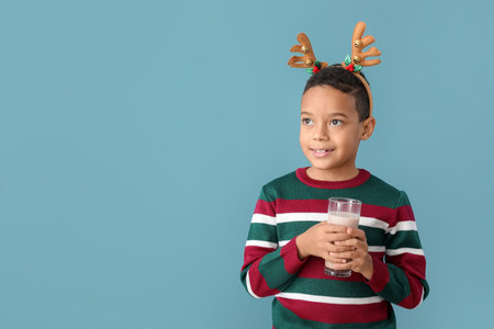 African-American boy with Christmas decor and tasty hot chocolate on color backgroundの写真素材