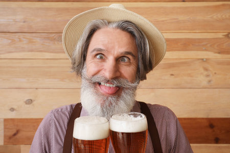Funny man in traditional German clothes and with beer on wooden backgroundの写真素材