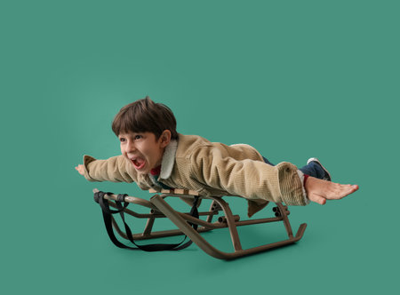 Sledding little boy on color backgroundの写真素材