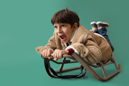 Sledding little boy on color backgroundの写真素材
