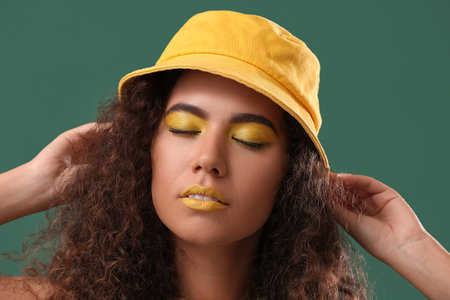 Beautiful African-American woman with makeup in yellow tones on color backgroundの写真素材