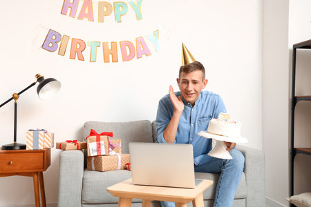 Young man celebrating Birthday online at home due to Coronavirus epidemicの写真素材