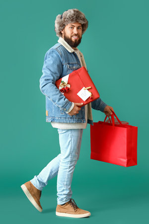 Walking man with Christmas gift and shopping bag on color backgroundの写真素材