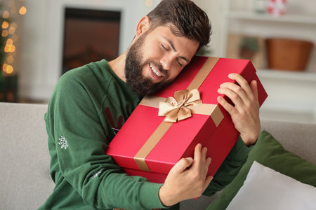 Happy man with Christmas gift at homeの写真素材
