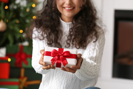 Happy woman with Christmas gift at homeの写真素材
