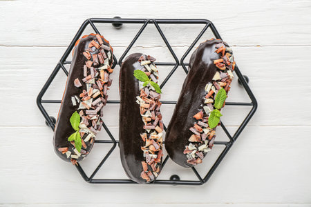 Grid with delicious chocolate eclairs on white wooden table