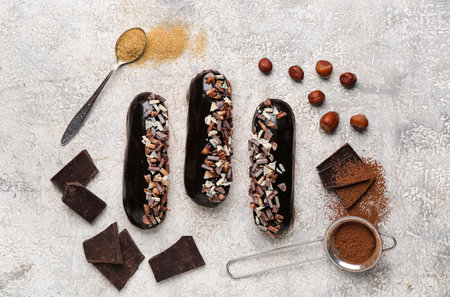 Composition with tasty chocolate eclairs and ingredients on light background