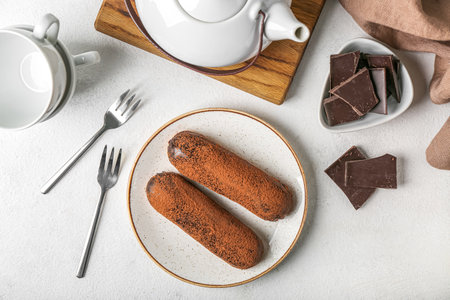 Plate with delicious chocolate eclairs on light table