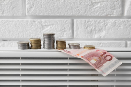 Radiator with money near white brick wall, closeup. heating season conceptの写真素材