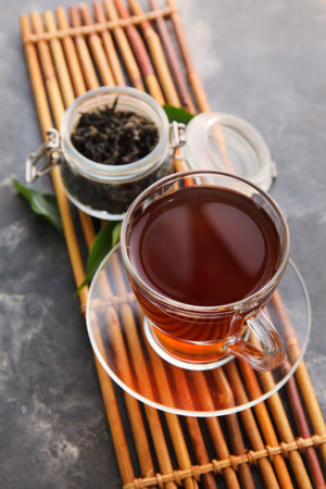Bamboo mat with cup of black tea on grunge background, closeupの写真素材