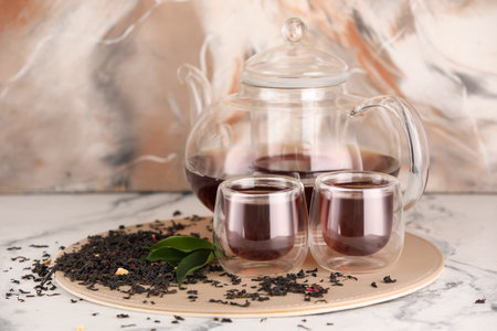 Glass cups and teapot of black tea on table