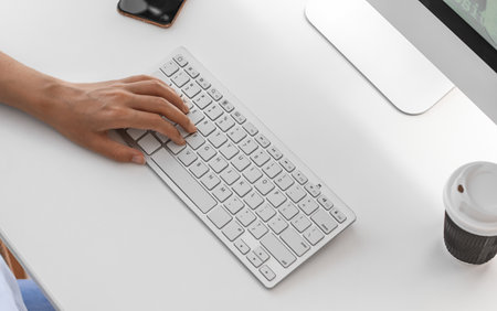 Young woman working with computer at table in office, closeup