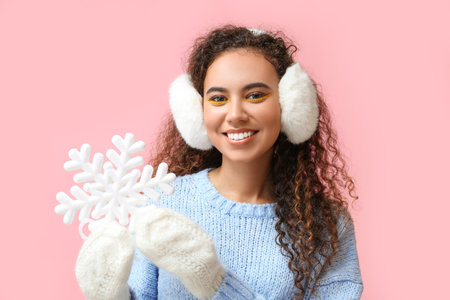 Beautiful African-American woman with big snowflake on pink backgroundの写真素材