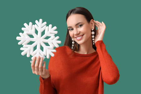 Beautiful woman in pearl earrings with big snowflake on green backgroundの写真素材