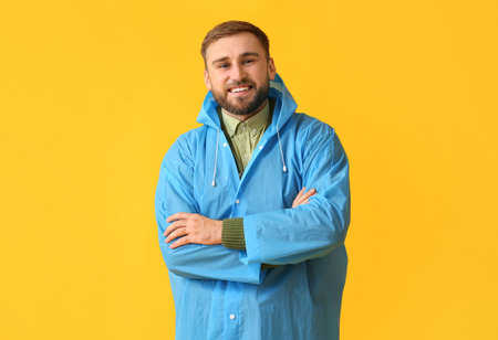 Young man in stylish raincoat on color backgroundの写真素材