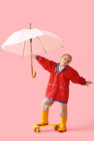 Little girl in stylish raincoat, with umbrella and skateboard on color backgroundの写真素材