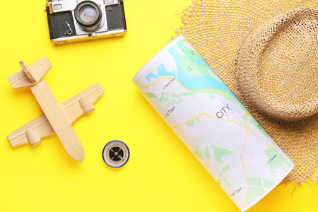 World map, photo camera, wooden plain and compass on yellow background