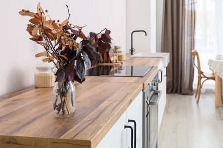 Vase with autumn branches on wooden counter in stylish kitchenの写真素材