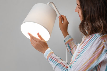 Woman with glowing standard lamp near light wall, closeupの写真素材